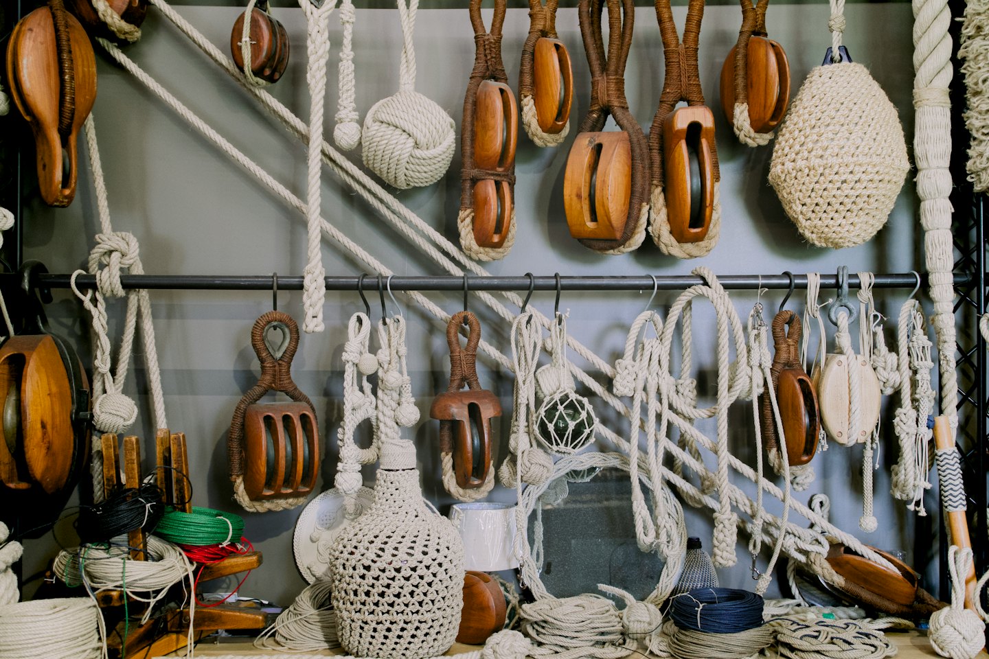 Nautical ropes, wooden pulleys, and knots arranged on a table.