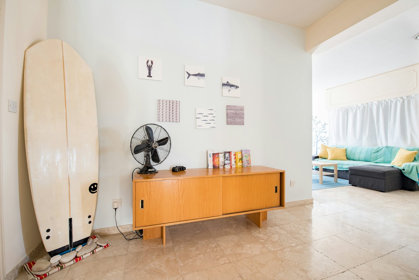 Cream surfboard leaning against pale blue wall in a living room.